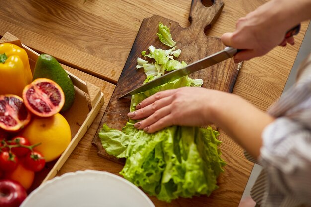 La mujer está preparando ensalada de verduras en la cocina