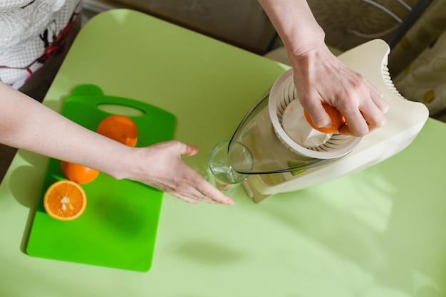 La mujer está preparando jugo de naranja fresco en la cocina Vista desde arriba