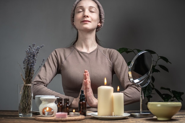 La mujer está realizando rituales para la relajación Una lámpara aromática con aceites esenciales sobre la mesa quemando velas Concepto de meditación armonía y procedimientos de cuidado del equilibrio en una atmósfera de calma