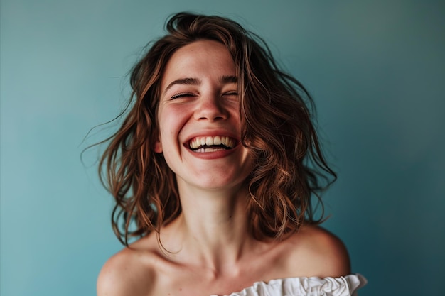 Una mujer está riendo y sonriendo frente a un fondo azul