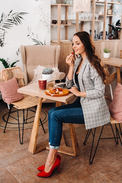 Una mujer está sentada en un café y comiendo fresas. Una niña con fresas en sus manos en una cafetería.