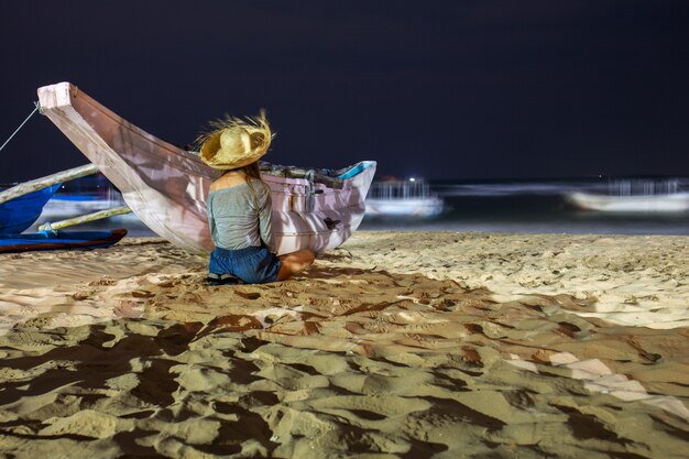 La mujer está sentada cerca del bote.