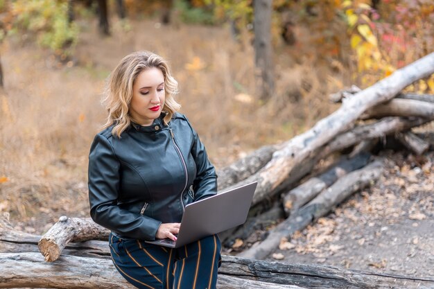 Una mujer está sentada en una computadora portátil en el parque en un registro