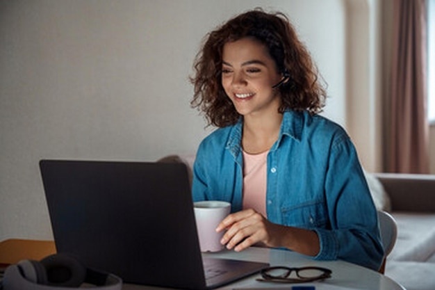 una mujer está sentada en una mesa con una computadora portátil y una taza de café