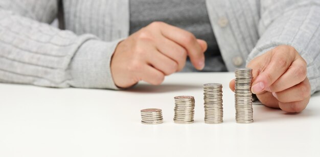 La mujer está sentada en la mesa y una pila de monedas sobre la mesa. Cálculo de gastos e ingresos, subvención, impuestos.