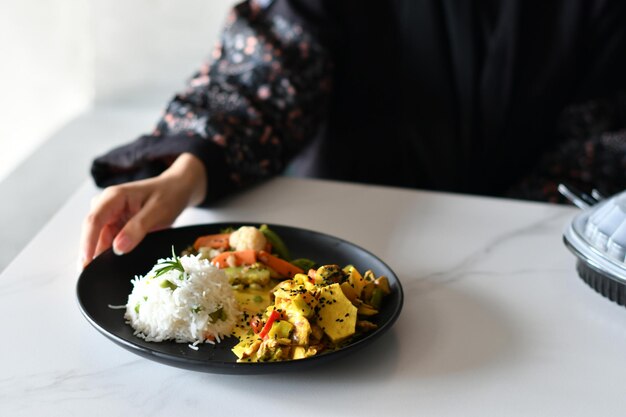 Una mujer está sentada en una mesa con un plato de comida que tiene escrita la palabra comida.