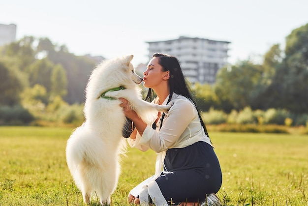 La mujer está sentada en el suelo del campo con su lindo perro