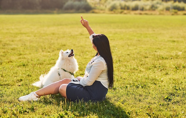 La mujer está sentada en el suelo del campo con su lindo perro