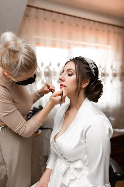 Una mujer está siendo maquillada por una mujer con una túnica blanca
