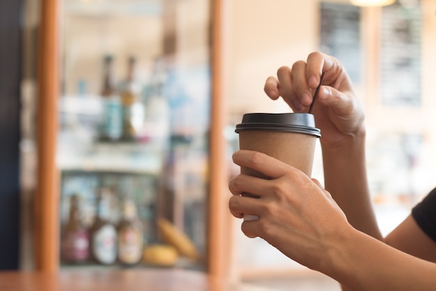 Una mujer está sosteniendo una taza de café en la cafetería al mediodía