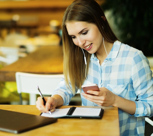 La mujer está tomando café y leyendo las noticias de la mañana por la conexión a Internet del teléfono móvil