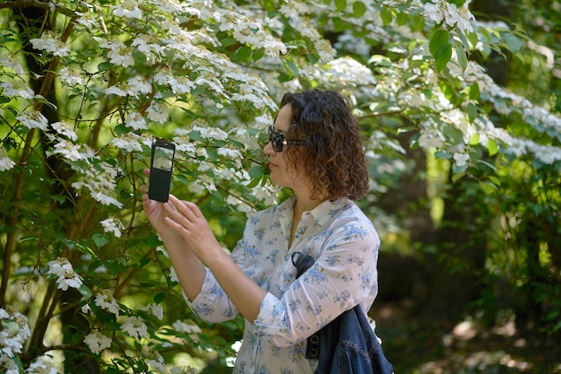 Una mujer está tomando fotos de flores de un viburnum.