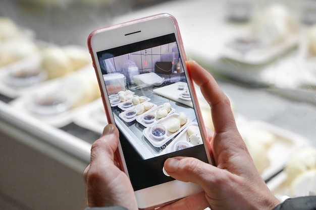 Mujer está tomando fotos móviles de preparación de alimentos en un restaurante