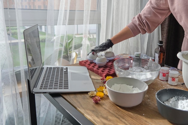 La mujer está tomando una lección en línea o viendo un video sobre cómo crear bombas de baño