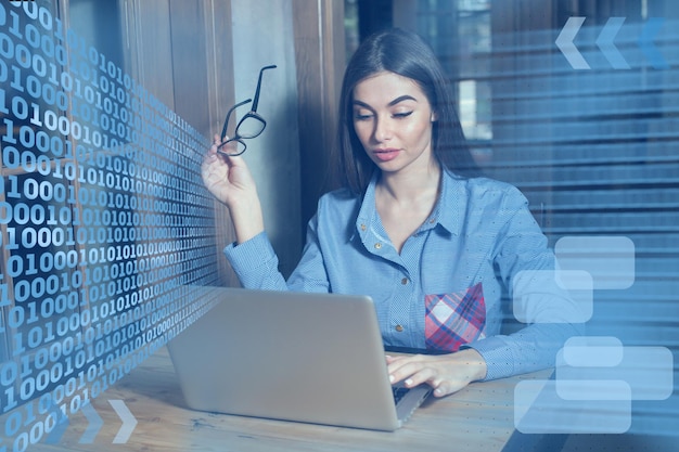 La mujer está trabajando con una computadora portátil y gafas en la mano.