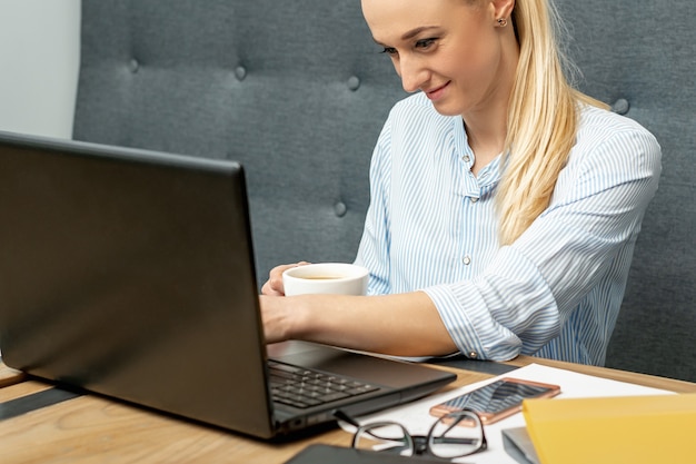 La mujer está trabajando en la computadora portátil en la oficina en casa.