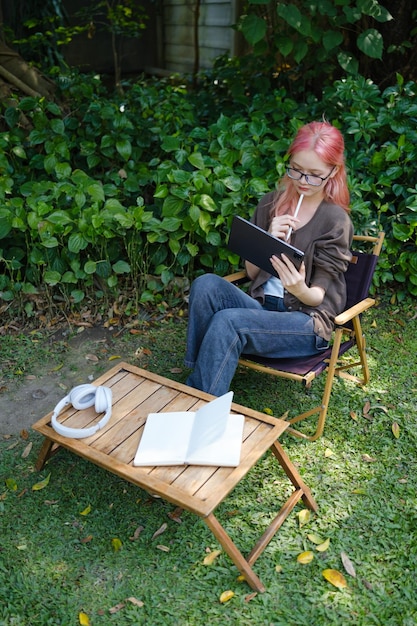 La mujer está usando una tableta digital en el jardín