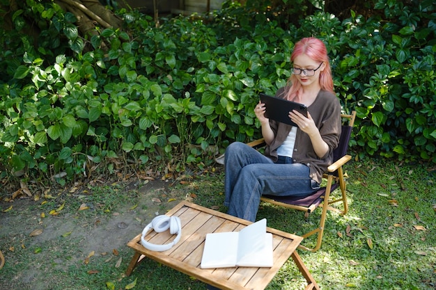 La mujer está usando una tableta digital en el jardín