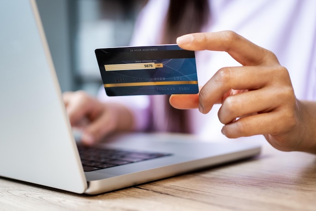 Una mujer está usando una tarjeta de crédito para pagar las compras en línea en una computadora portátil que se conecta a Internet