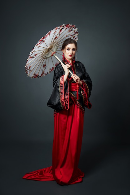 La mujer está vestida con ropa tradicional japonesa china roja.