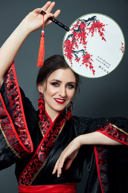 La mujer está vestida con ropa tradicional japonesa china roja.