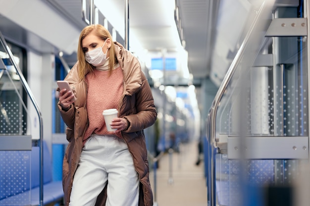 Mujer en la estación de metro con máscara protectora de higiene quirúrgica en la cara evita el riesgo de coronavirus