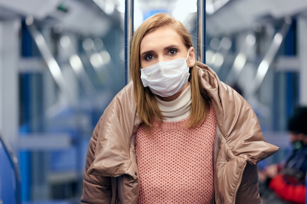 Foto mujer en la estación de metro con máscara protectora de higiene quirúrgica en la cara evita el riesgo de coronavirus