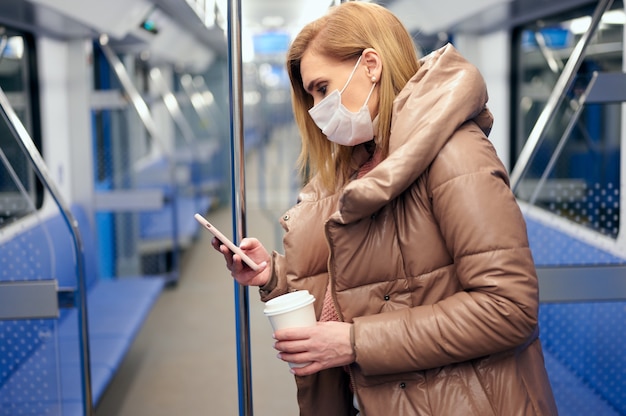 Mujer en la estación de metro con máscara protectora de higiene quirúrgica en la cara evita el riesgo de coronavirus