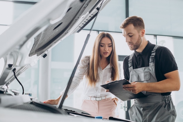 Mujer en la estación de servicio acr comprobando su coche con un mecánico