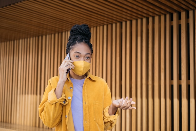 Mujer estadounidense con mascarilla protectora hablando por teléfono móvil Centro de atención al cliente de llamadas