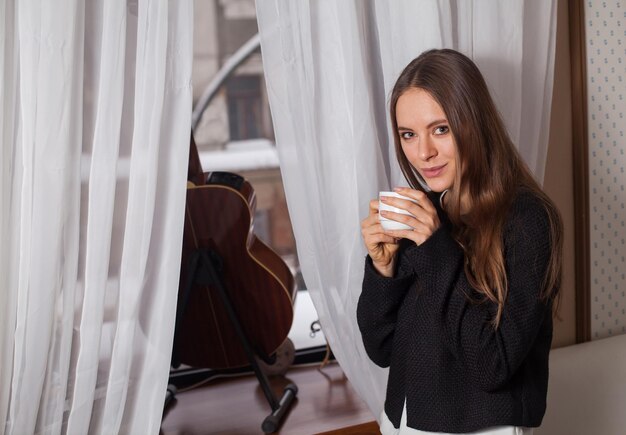 mujer estar de pie, cerca, ventana, y, bebida, café