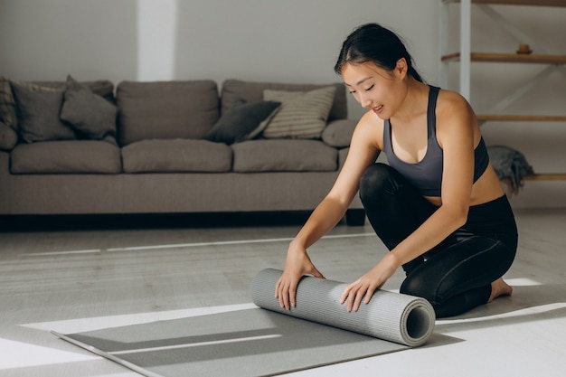 Mujer con estera de yoga en casa