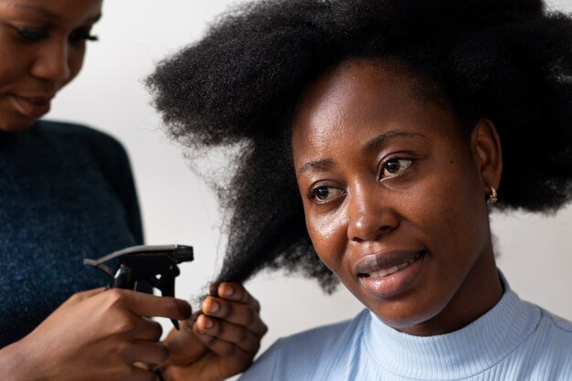 Mujer estilista cuidando el cabello afro de su cliente