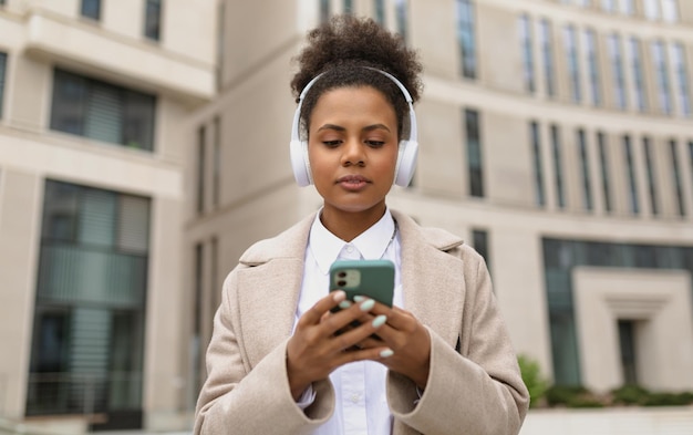 Mujer con estilo afroamericana en auriculares en el fondo de un centro de negocios tiene un teléfono en