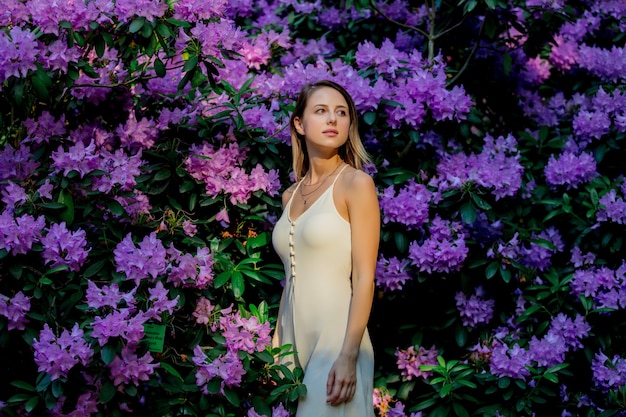 Mujer de estilo cerca de flores de rododendro en un jardín en primavera