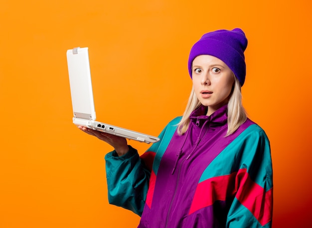 Mujer de estilo en chándal de los años 90 con cuaderno en naranja