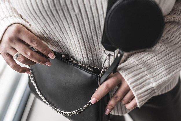 Mujer con estilo elegante joven que sostiene un bolso de cuero negro fresco