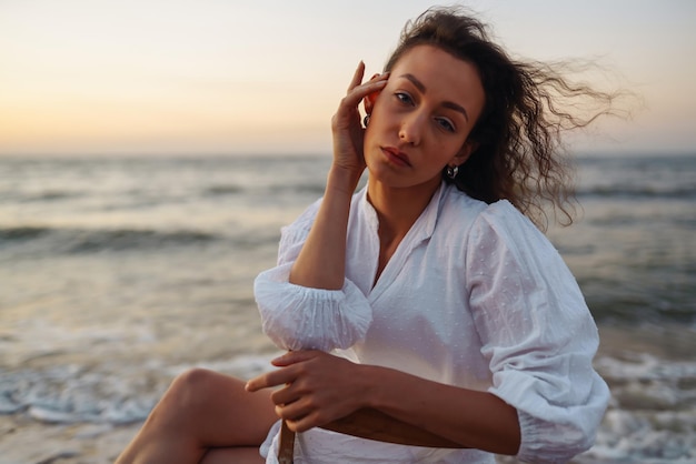 Mujer con estilo en elegante vestido blanco posando cerca del mar Horario de verano Viaje fin de semana relajarse