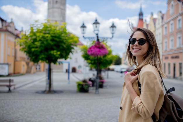 Mujer de estilo con gafas de sol y mochila en la plaza del centro de la ciudad de edad. Polonia