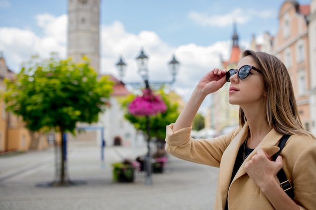 Mujer de estilo con gafas de sol y mochila en la plaza del centro de la ciudad de edad. Polonia