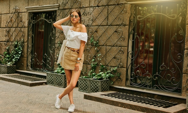 Mujer con estilo de moda en ropa de moda y gafas de sol posando al aire libre