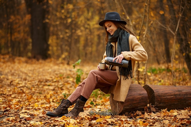 Mujer con estilo pasa tiempo en la naturaleza otoñal