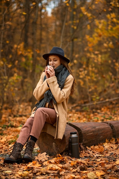 Mujer con estilo pasa tiempo en la naturaleza otoñal