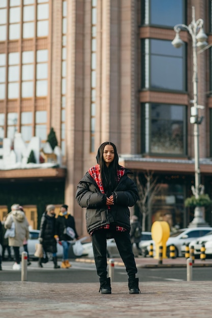 Mujer con estilo en ropa de gran tamaño de moda se encuentra en la calle de la metrópolis