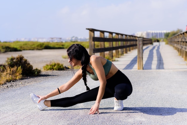 Mujer estirando la pierna en el camino