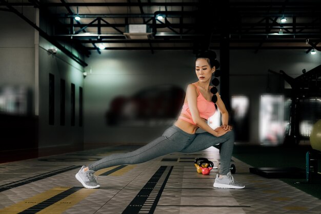 Foto mujer estirando la pierna en el gimnasio