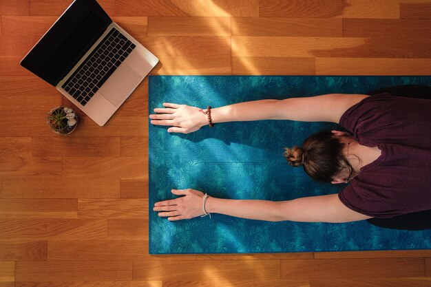 Mujer estirando sobre una estera durante la clase de yoga online