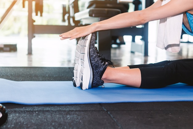 Foto mujer estirando su pierna para calentar el ejercicio en el gimnasio