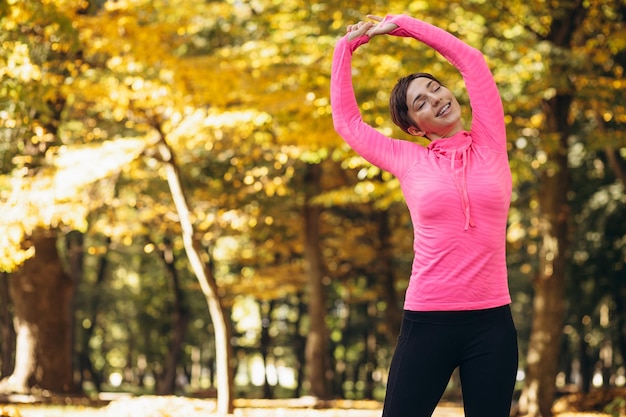 Mujer estirándose en el parque de otoño por la mañana