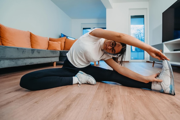 Una mujer estirándose en su apartamento temprano en la mañana después del entrenamiento, lo que refleja su dedicación a